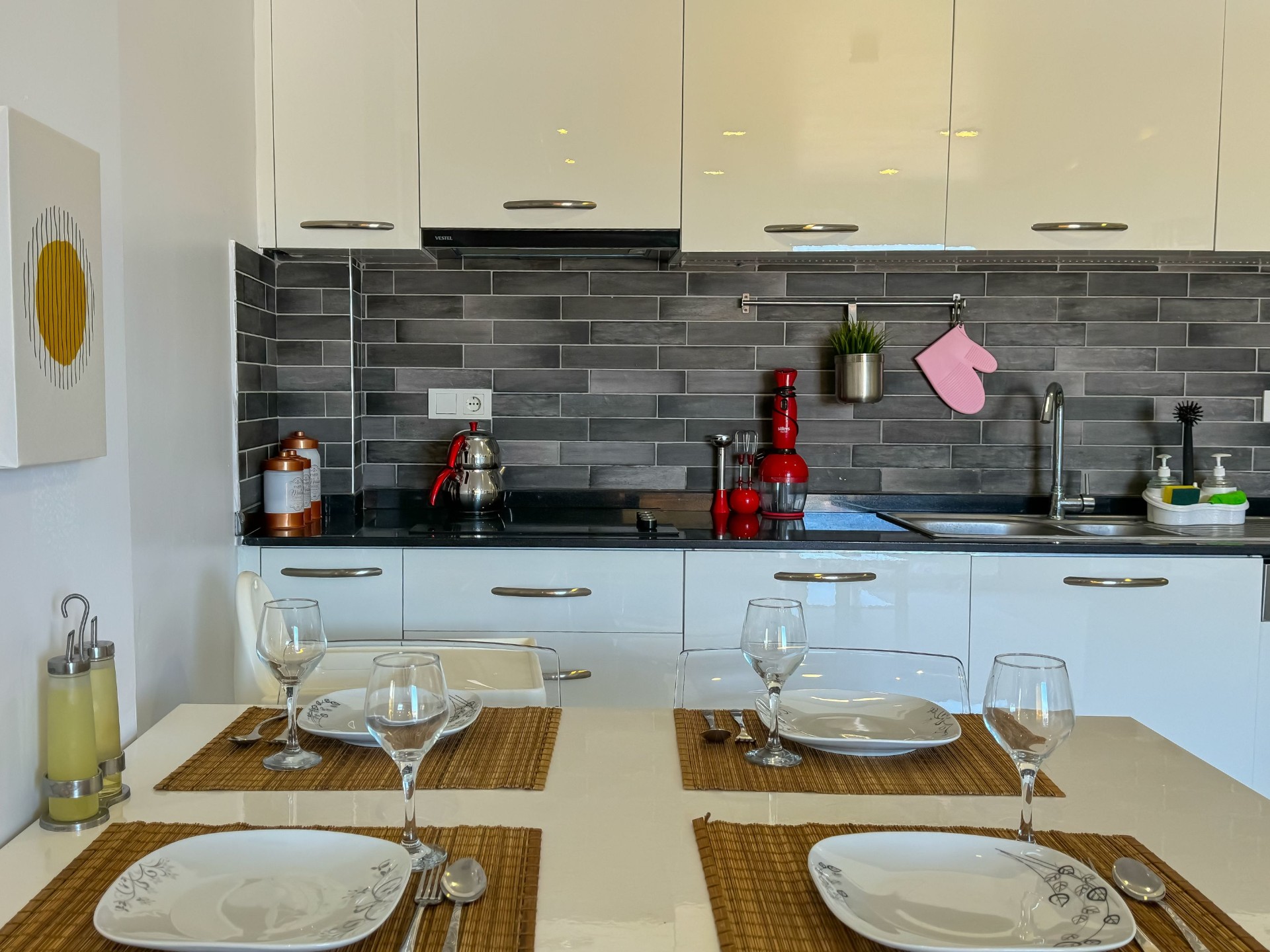 Modern open kitchen with white cabinetry and dark stone backsplash
