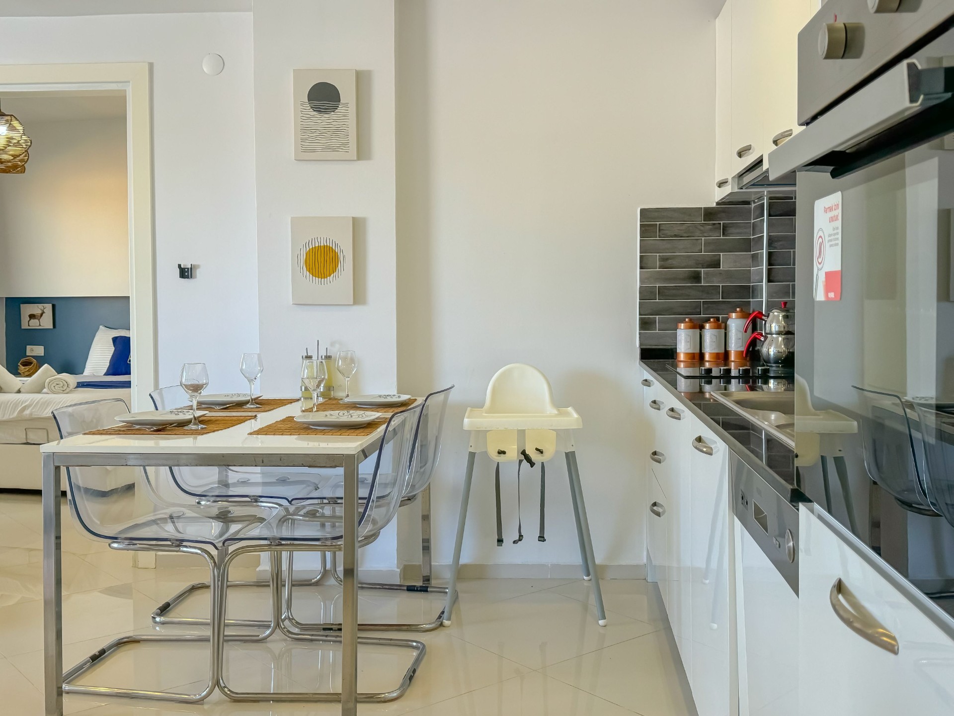 Kitchen and dining area with high chair and view through to the bedroom