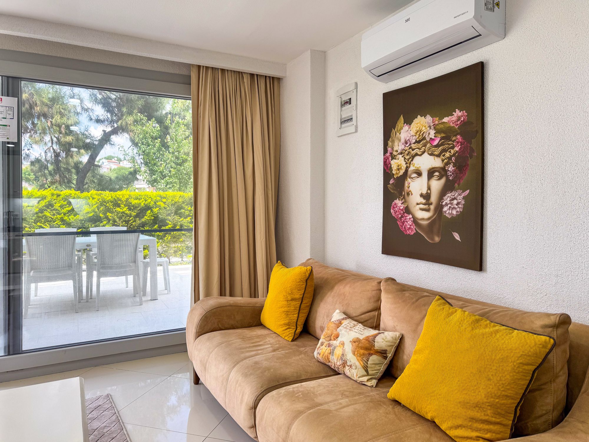 Lounge sofa with statement artwork beside floor-to-ceiling doors opening to the garden terrace