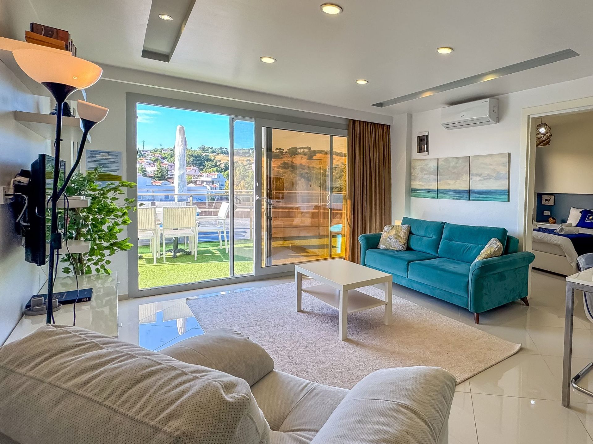 Living room with turquoise sofa, sea view and access to the master bedroom
