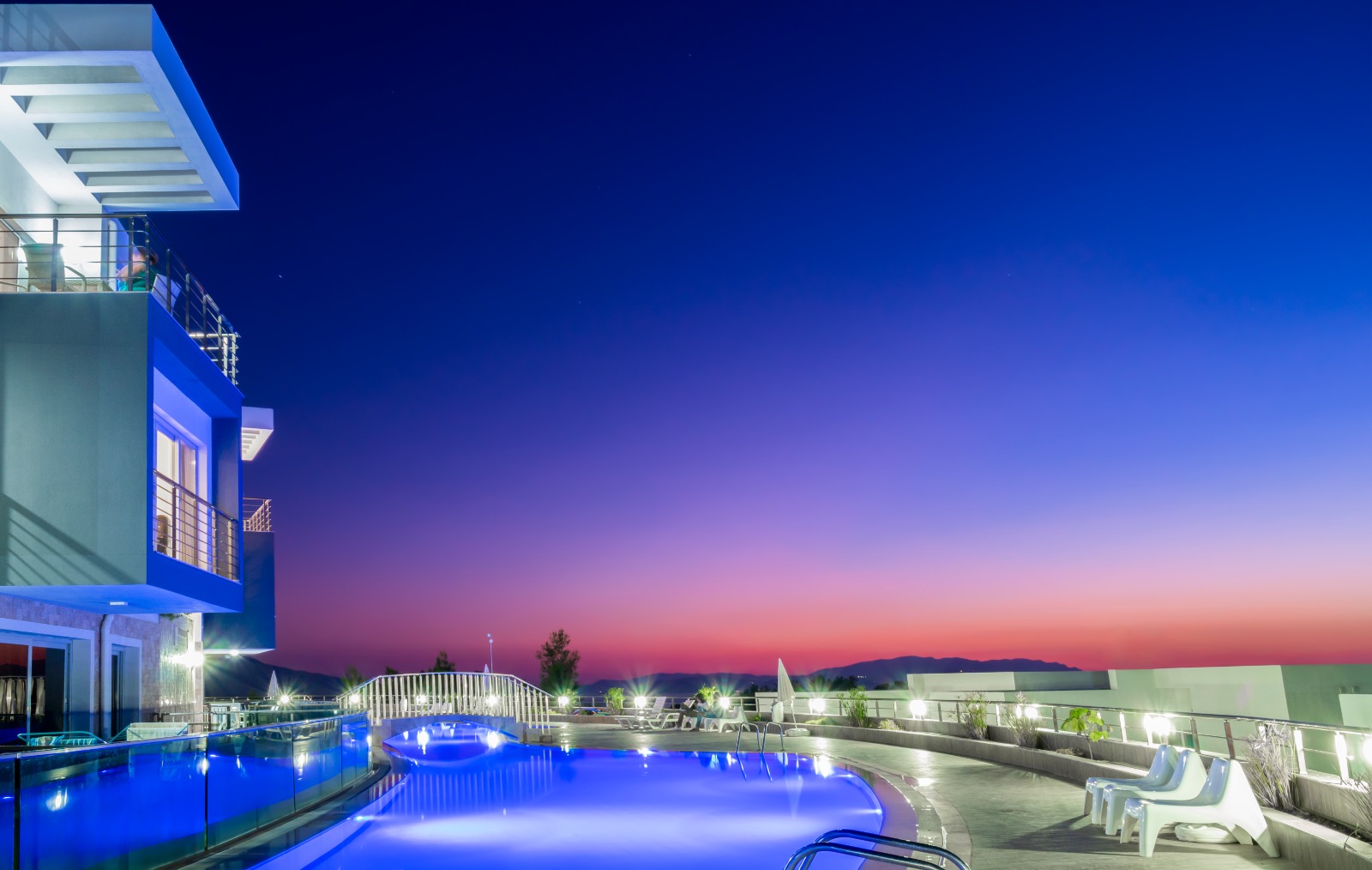 Lavender Residence at golden hour, pale stone buildings in the pine forest above the Aegean